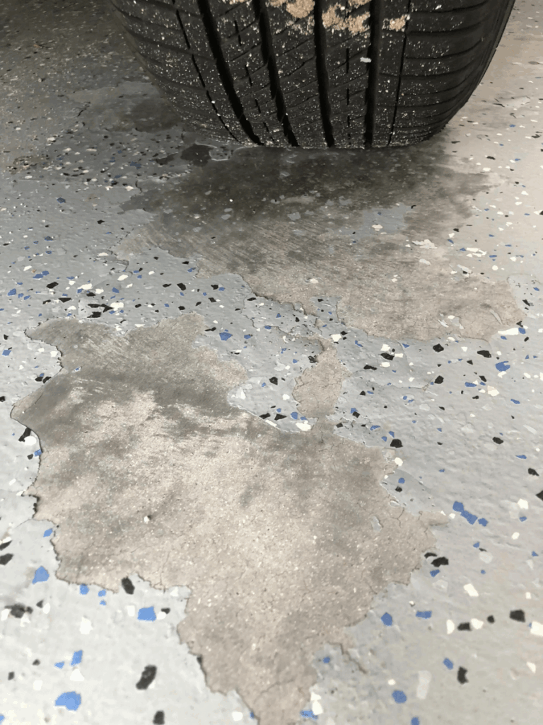Close-up photo of a failed DIY epoxy coating showing peeling, bubbling, hot tire pickup marks, or yellowing from UV damage.