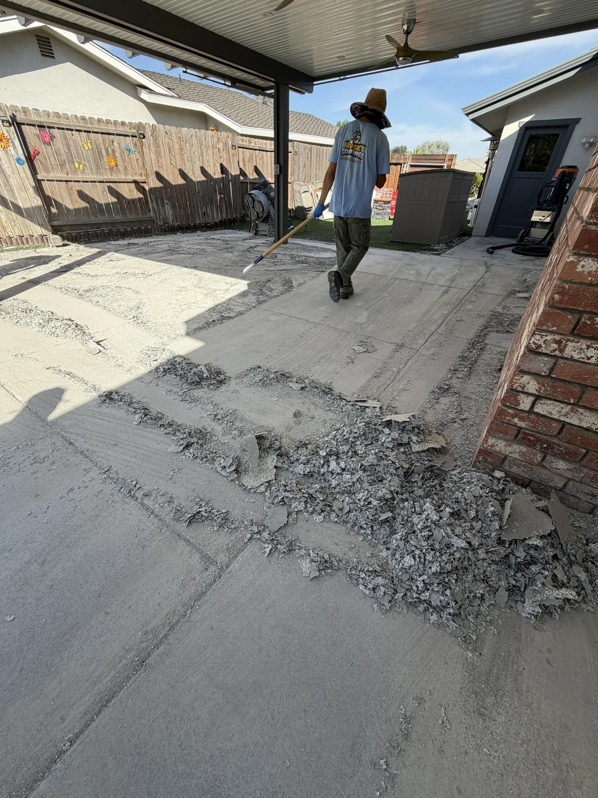 Husky Coatings crew removing a failed floor coating from a covered patio in Bakersfield, CA
