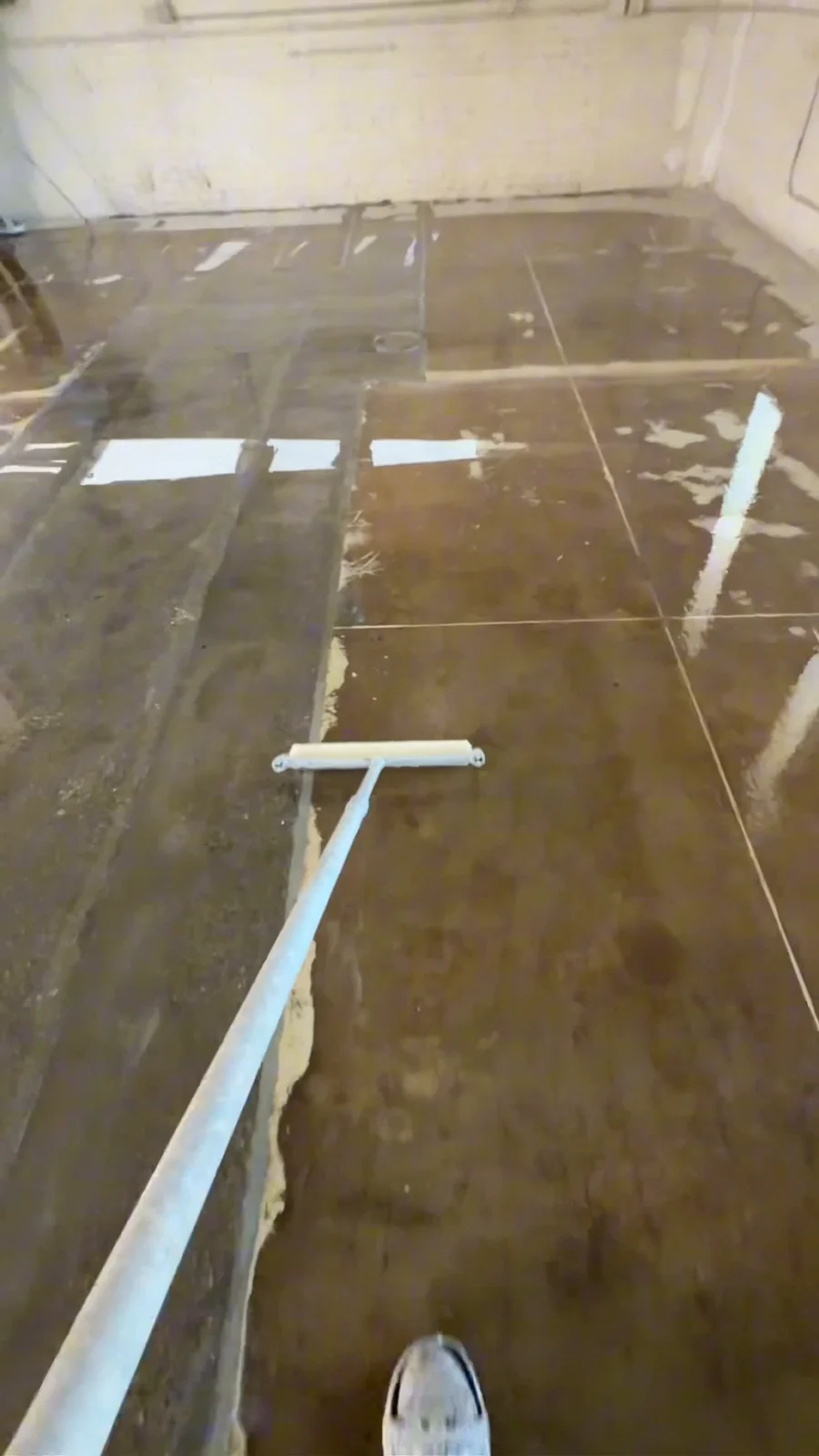 Husky Coatings crew rolling moisture vapor barrier primer on a commercial slab in Bakersfield, CA