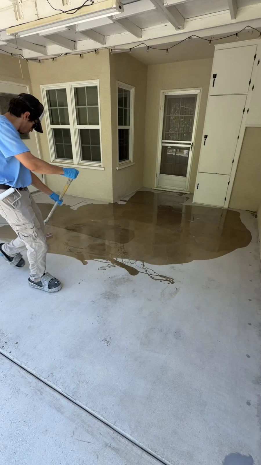 Husky Coatings crew squeegeeing moisture vapor barrier primer onto a patio slab in Bakersfield, CA